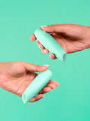 two hands holding a green lipstick vibrator each