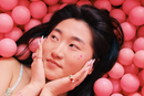 person smiling with their hands on their cheeks in a pink ball pit