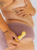 person holding The Tennis Pro yellow G-spot vibrator against their hip