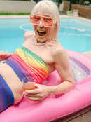 very happy woman on a pool lilo in a rainbow tube top