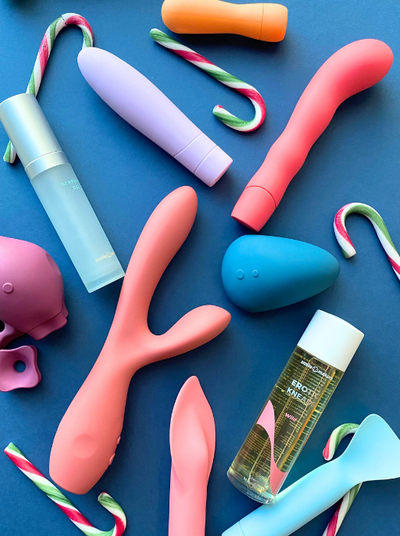 a flatlay of Smile Makers' vibrators, lube and candy canes on a navy blue background
