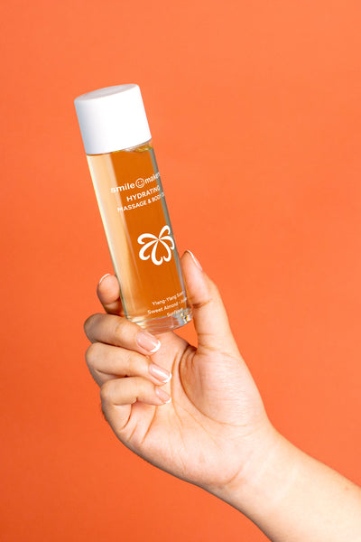 Hand holding a bottle of skincare product against an orange background